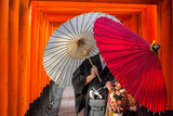Fototapeta Bambus - Couple with traditional japanese umbrellas posing at torii gates in Kyoto