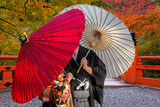 Fototapeta Bambus - Couple with traditional japanese umbrellas posing at autumnal park in Kyoto
