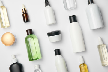 top view of various cosmetic bottles and containers on white background