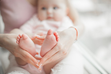 Wall Mural - Baby`s feet closeup picture. Mother`s hands holding child`s foot. Little girl`s fingers at front. Background of parenthood.