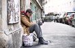 Leinwandbild Motiv Homeless beggar man sitting outdoors in city asking for money donation.