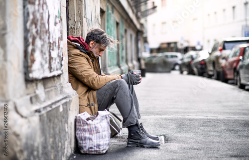 Cuadros en Lienzo Homeless beggar man sitting outdoors in city asking for money donation
