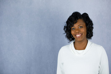 Beautiful African Amercian Woman in a white sweater with a grey background