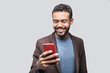 © kite_rin - Portrait of handsome cheerful smiling young man using smartphone isolated on gray background. Laughing joyful men with mobile phone studio shot