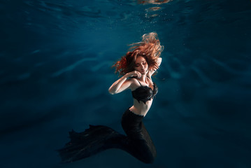 Underwater beautiful red hair freediver girl with mermaid tale