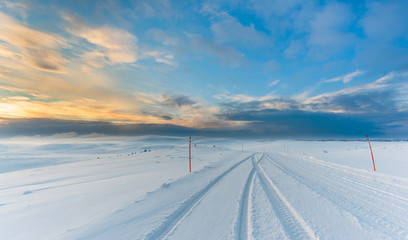 Wall Mural - epic arctic road trip. ice road with tire tracks on snow in arctic landscape with the blue sky start