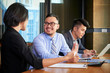 © DragonImages - Smiling Asian businessman talking to his female coworkers about company development