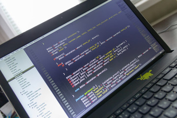 Modern software development background: nice looking laptop with programm on display.