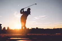Young Junior Golfer Practicing In A Driving Range With Beautiful Sunset Light In Winter.