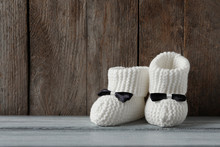 Handmade Baby Booties On Table Against Wooden Background. Space For Text