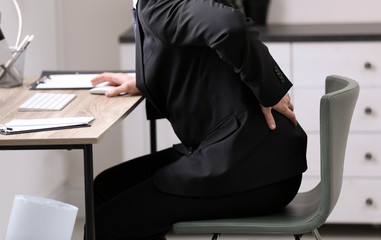 Canvas Print - Businessman suffering from back pain at workplace, closeup