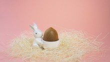 Creative Layout Made Of White Ceramic Bunny Holds A Kiwi As Easter Egg On Pink Background. Minimal Style Of Concept For Gift Or Blog, Easter, Healthy Lifestyle. Horizontal, Copy Space