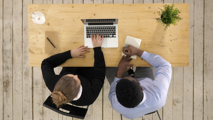 Two entrepreneurs sitting together working in an office desk putting notes to notebook