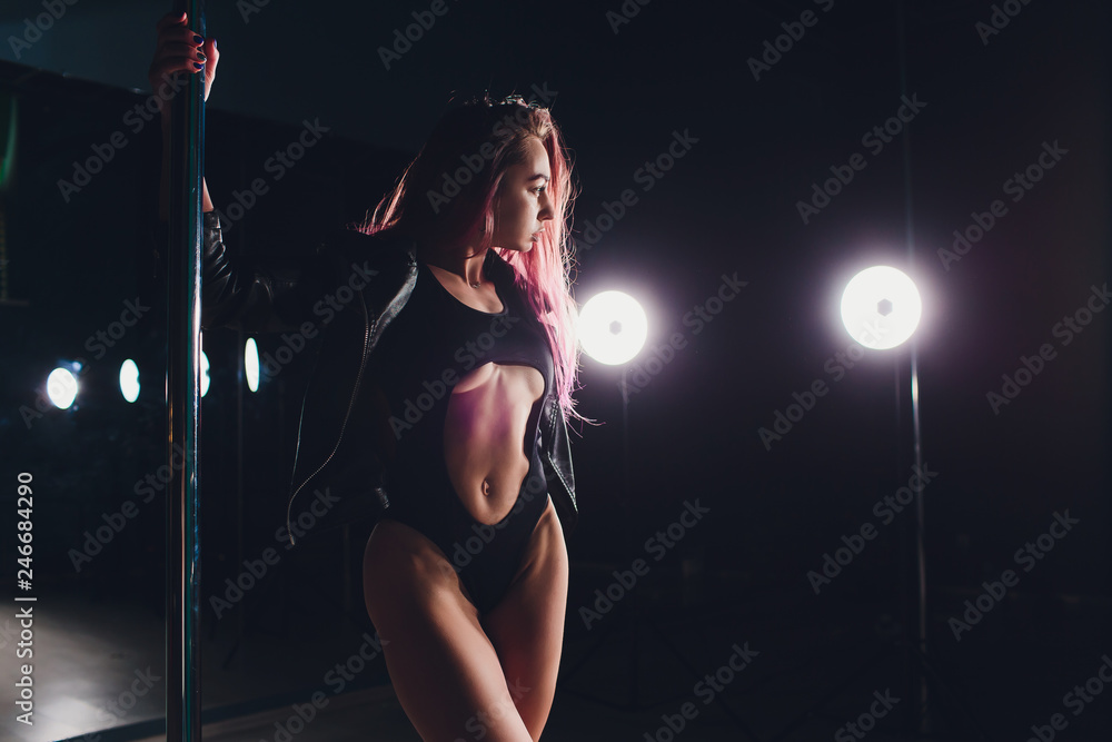 Red haired pole dance girl exercises and poses on the pylon in the smoke on the black background. - obrazy, fototapety, plakaty 