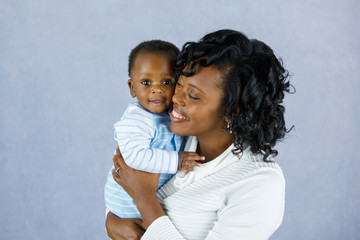 Beautiful African Amercian Woman wHolding Her Baby boy on a Gray Background