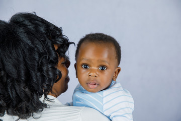 Wall Mural - Beautiful African Amercian Woman wHolding Her Baby boy on a Gray Background