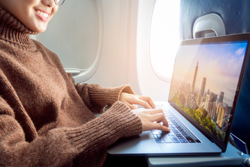 Beautiful Asian woman is working with laptop in airplane