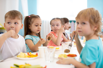 Wall Mural - Group of kindergarten children have lunch in daycare