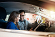 © littlewolf1989 - Happy couple in car interior at vehicle dealership showroom.