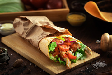 Wall Mural - Tasty mexican food burrito with vegetables, spicy salsa sauce and vegetables on dark wooden rustic background