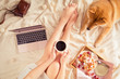 Top view and flat lay of woman in bed with laptop at home, red Shiba Inu dog, cup of coffee and belgian waffles on hygge background. Flatlay of feminine blogger working place in Kawaii style