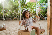 Portrait Of A Happiness Little Girl Laughing When Playing A Swing Alone