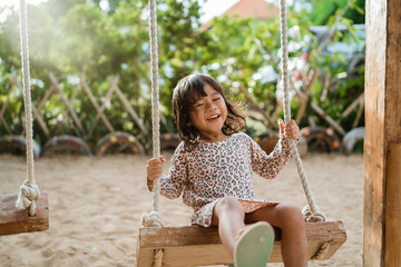 portrait of a happiness little girl laughing when playing a swing alone