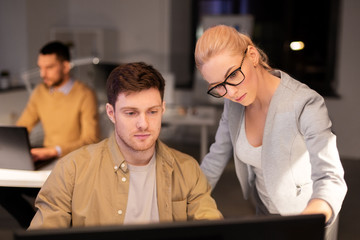 business, deadline and technology concept - coworkers with computer working late at night office