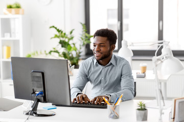 business, people and technology concept - african american businessman with computer working at office