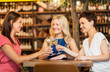 © Syda Productions - people, celebration and lifestyle concept - happy women drinking wine and clinking glasses at bar or restaurant