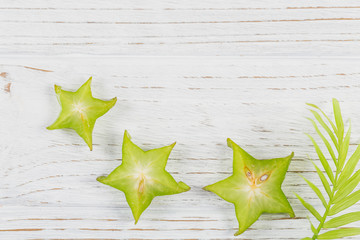 Green palm leaves and tree fresh tropical slices of carambola fruits