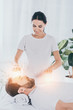 smiling young female healer doing reiki session to calm bearded man with closed eyes