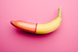 Pink condom on banana in front of pink background