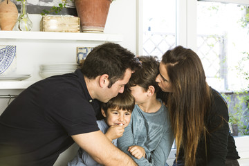 Portrait of a happy family kissing and hugging at home. Family lifestyle showing affection