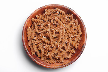 Wall Mural - Raw brown pasta in wooden bowl. Food container isolated on white in studio. Cooking background.