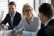 © fizkes - Friendly middle aged female leader laughing at group business meeting, happy old businesswoman enjoying fun conversation with partner, smiling mature business coach executive talking to colleague