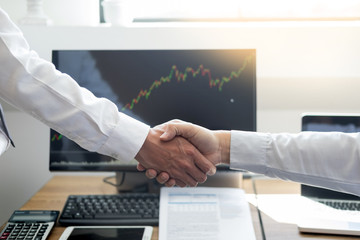 Wall Mural - shaking Hand between businessman of cooperation over Stock market chart, business trading concept.