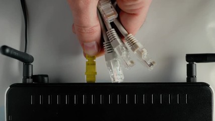 Wall Mural - A man connects the ethernet cable to the WAN and LAN ports of the WiFi router. Closeup