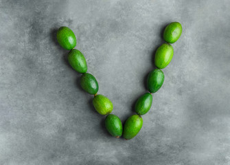 Letter V for vegan vegetables vitamins vitality made from ripe raw avocados on dark gray stone background. Creative flat lay. Food typography. Clean eating balanced diet