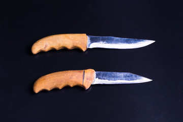 two knives with wooden handles are parallel on a black background