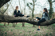 © GAGO IMAGES - Two friends sitting on a tree in the park and smiling