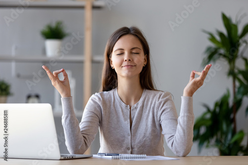 Calm Young Woman Worker Taking Break Doing Yoga Exercise At