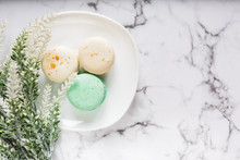 Violet Green White Macarons And Coffee Cup On Marble Table Background. Delicious Sweets And Coffee Break. Gift For Valentines, Mothers Day, Womans Day Concept. Close Up, Flat Lay, Top View