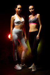 Two Asian Tan Skin Fitness women exercise boxing weight punch in Fog Smoke Dark background environment, studio lighting yellow back light copy space, concept 2 Woman Can Do Sport 6 packs