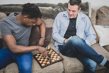 Wall Mural - A gay couple enjoying time indoors at home, playing chess. 