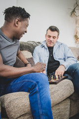 Wall Mural - A gay couple enjoying time indoors at home, playing chess. 