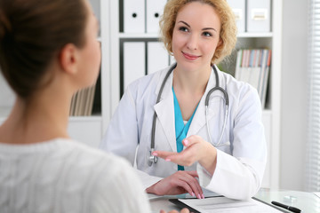 Wall Mural - Happy blonde female doctor and patient discussing medical examination results. Medicine, healthcare and help concept