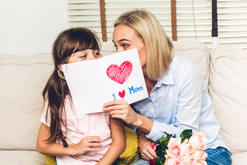 little daughter giving her mother a greeting card for surprise at mother's day.love of family and mo