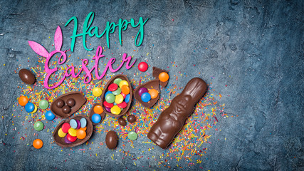 Color text of happy easter with chocolate traditional eggs, bunny and sugar sprinkles or confetti