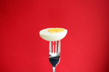 Wall Mural - Half boiled egg on a red background. Food on fork